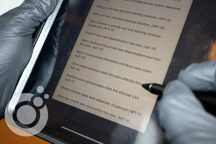 A person wearing gloves is using a stylus on a tablet screen displaying an inspection document with observations about water and mold issues, including signs of pest infestation and broken window seals.